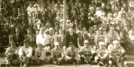 Une équipe de baseball assise devant la foule et des dignitaires, à l&#039;occasion du 25e annive...